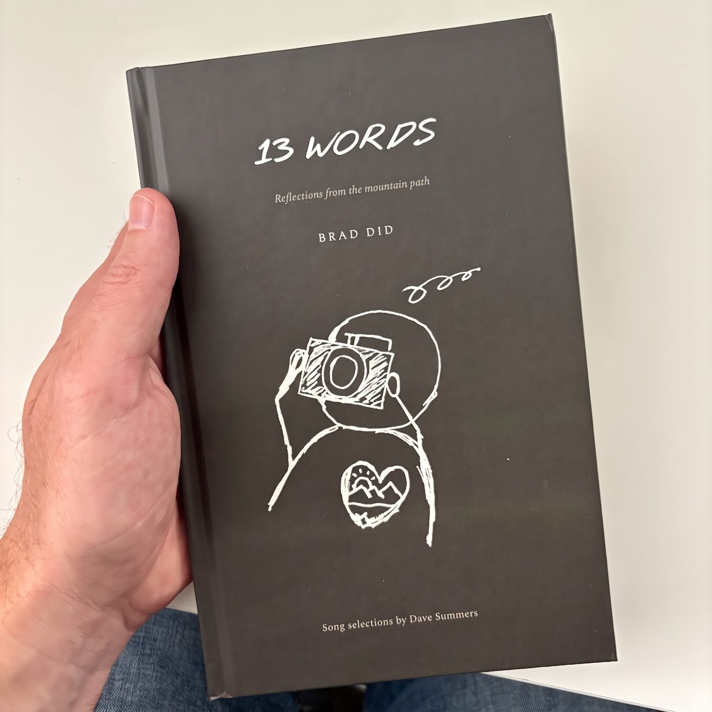 A hand holds 13 Words, front cover out.